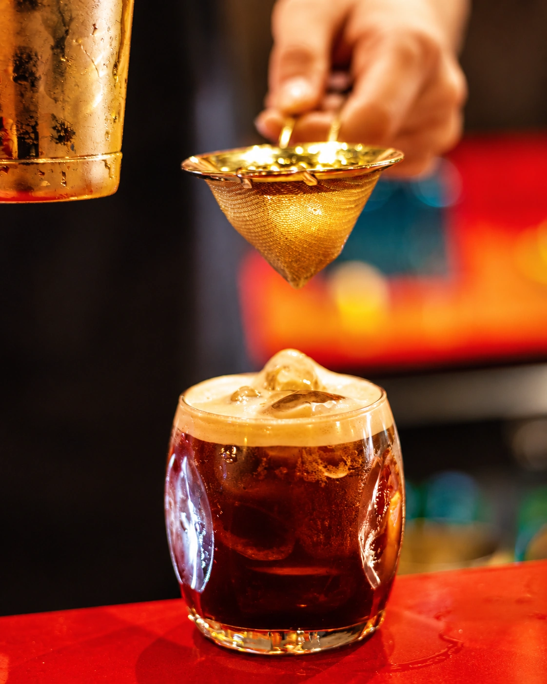 Un cocktail ambré préparé à la lumière chaleureuse du bar